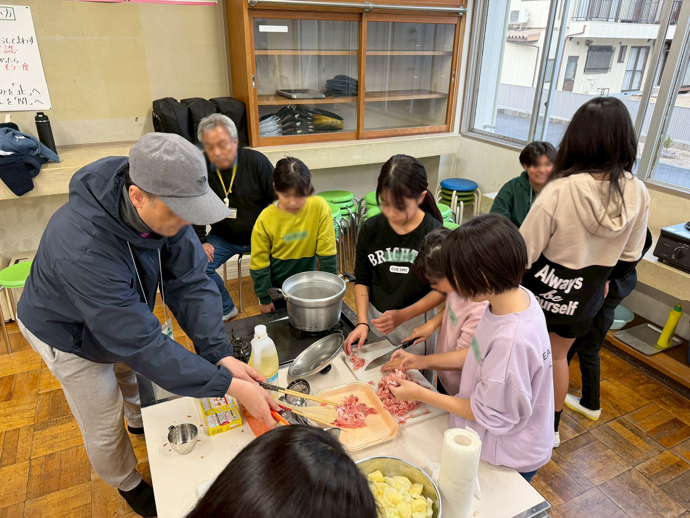 子どもが肉を切り、実行委員がそばで見守る様子